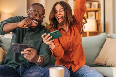 Happy couple playing video games and celebrating a win at home.