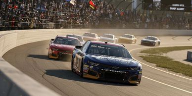 Race cars competing on a curved speedway track.